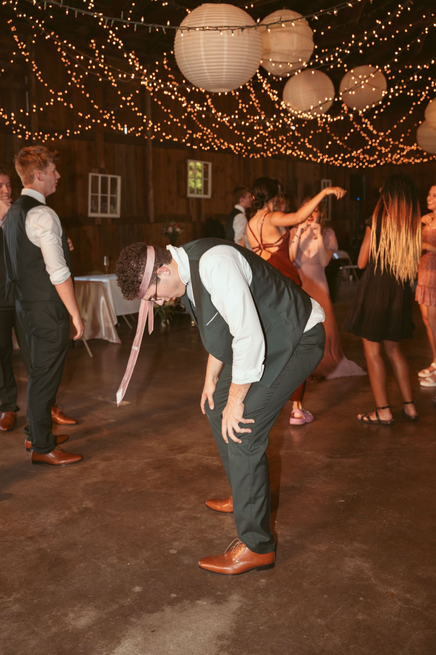 Dancers showing off their moves on a rustic venue floor under warm string lights.