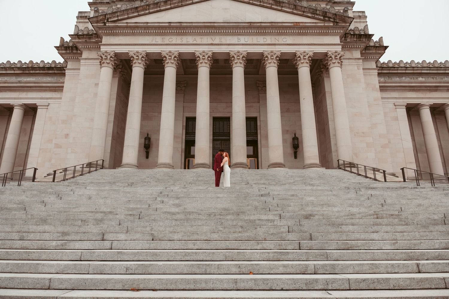 Grand neoclassical building with white stone columns and steps leading to an ornate entrance.