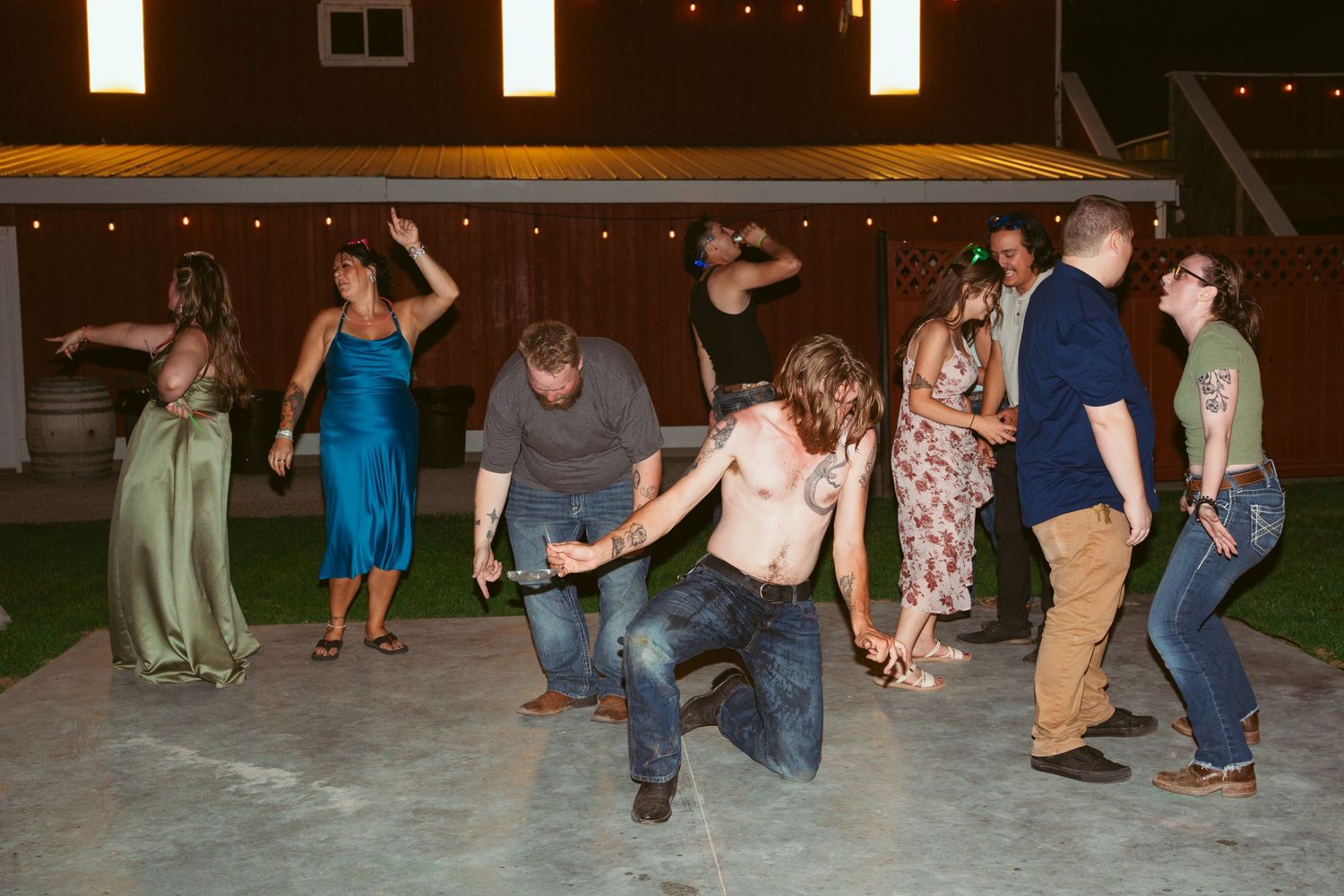 People dancing and having fun at an outdoor party under string lights.