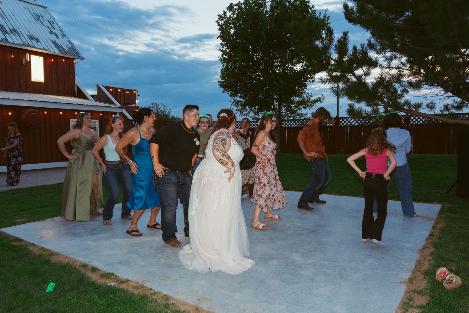 Wedding party dancing together on an outdoor patio under blue skies.