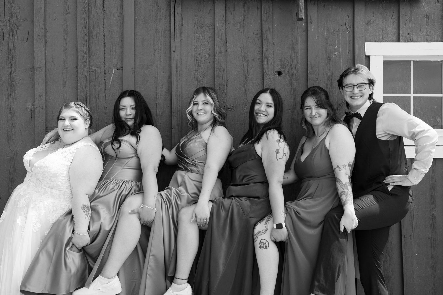 Black and white portrait of wedding party lined up against wall.
