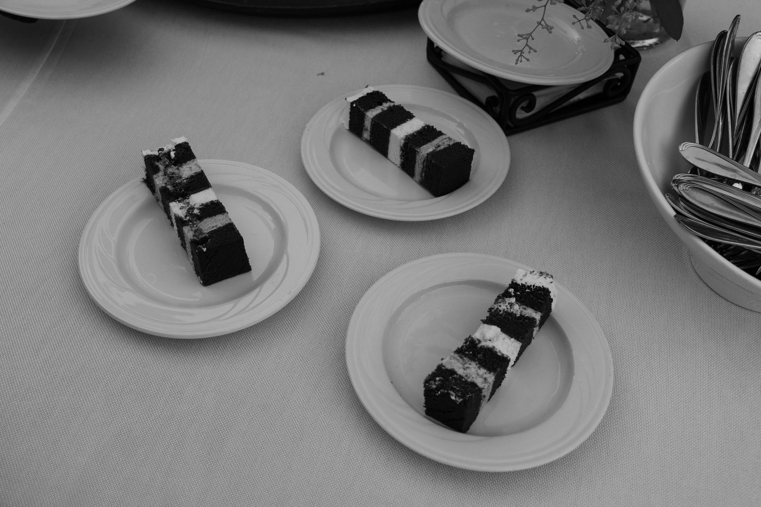 Black and white image of plated desserts on white dishes at a formal event.