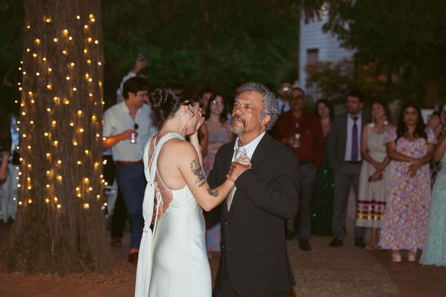 Evening wedding reception with string lights creating romantic ambiance outdoors.
