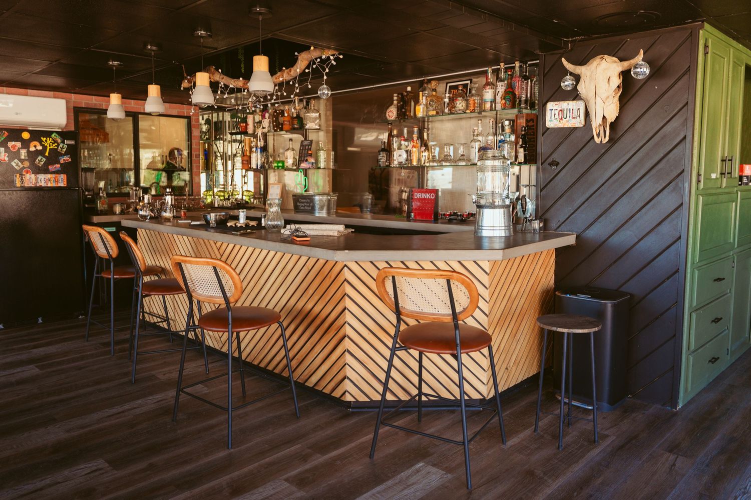 Modern bar interior with geometric wood paneling and industrial-style lighting fixtures.