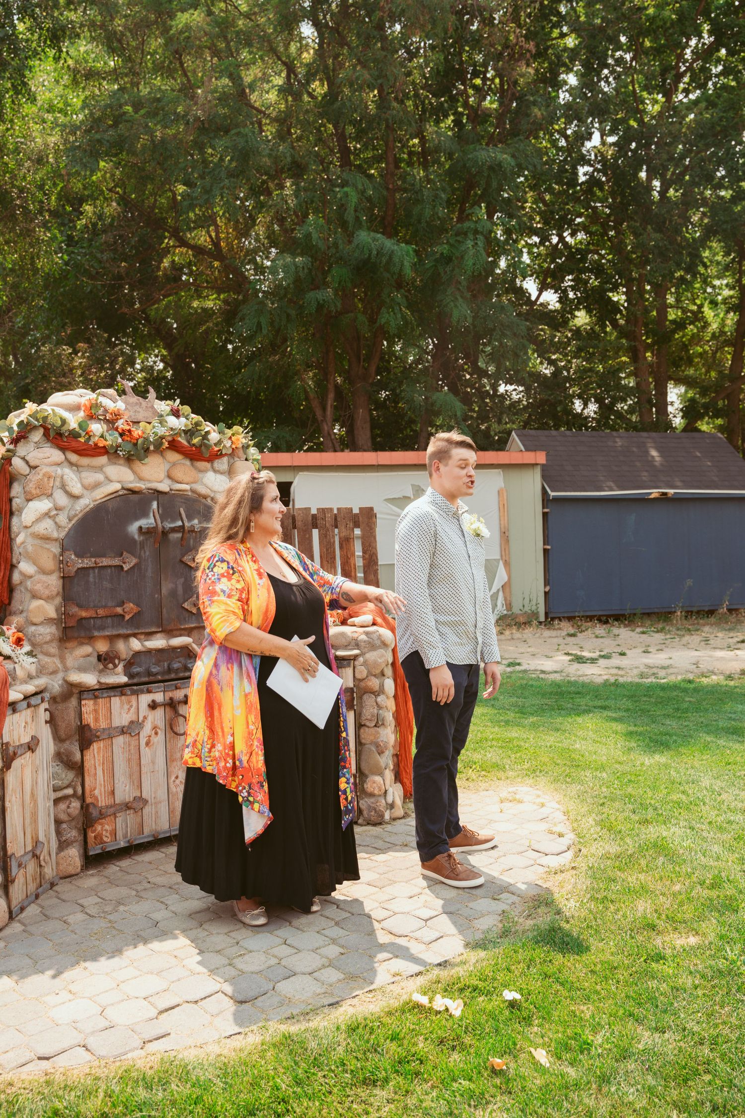 Wedding party members posing near a rustic stone wall with decorative elements.