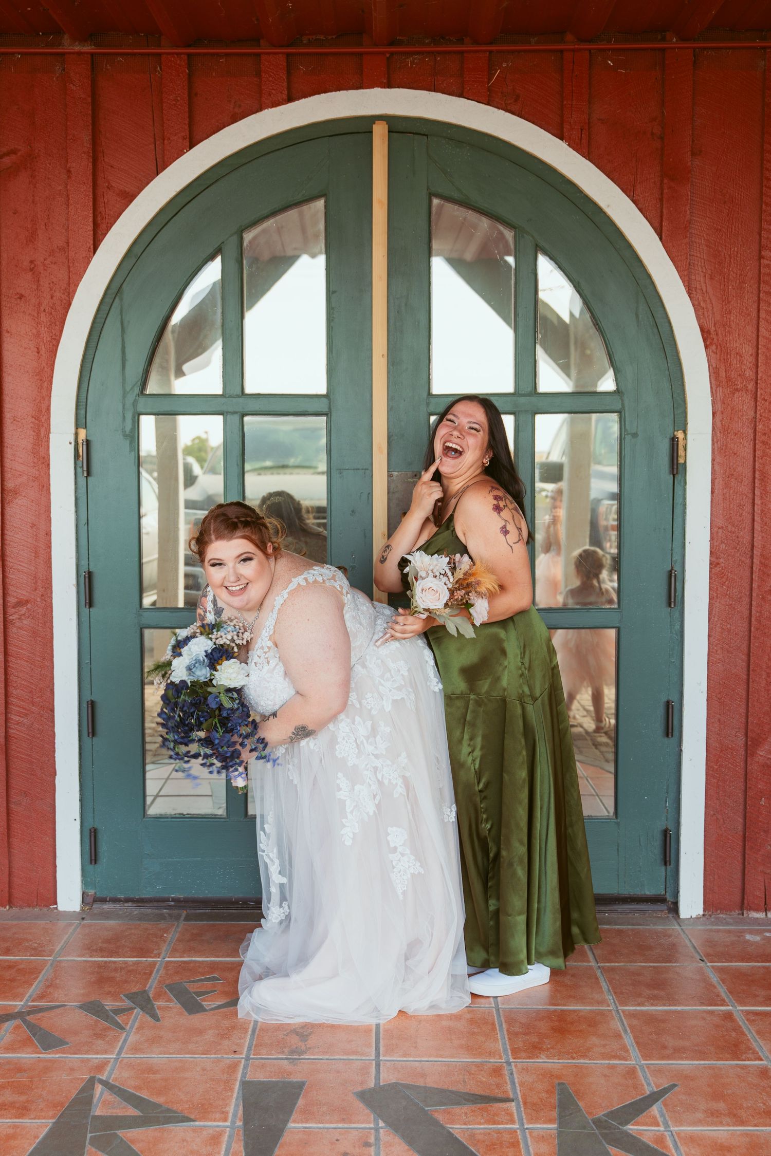 Playful wedding party poses for creative photo series in front of teal arched doors and red wall.