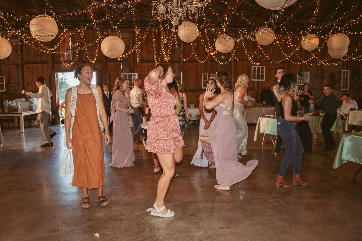 Party guests enjoying a lively dance under warm lighting and decorative lanterns.