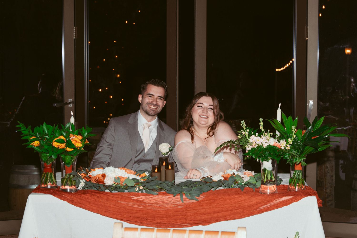 Wedding reception table decorated with floral arrangements and warm ambient lighting.