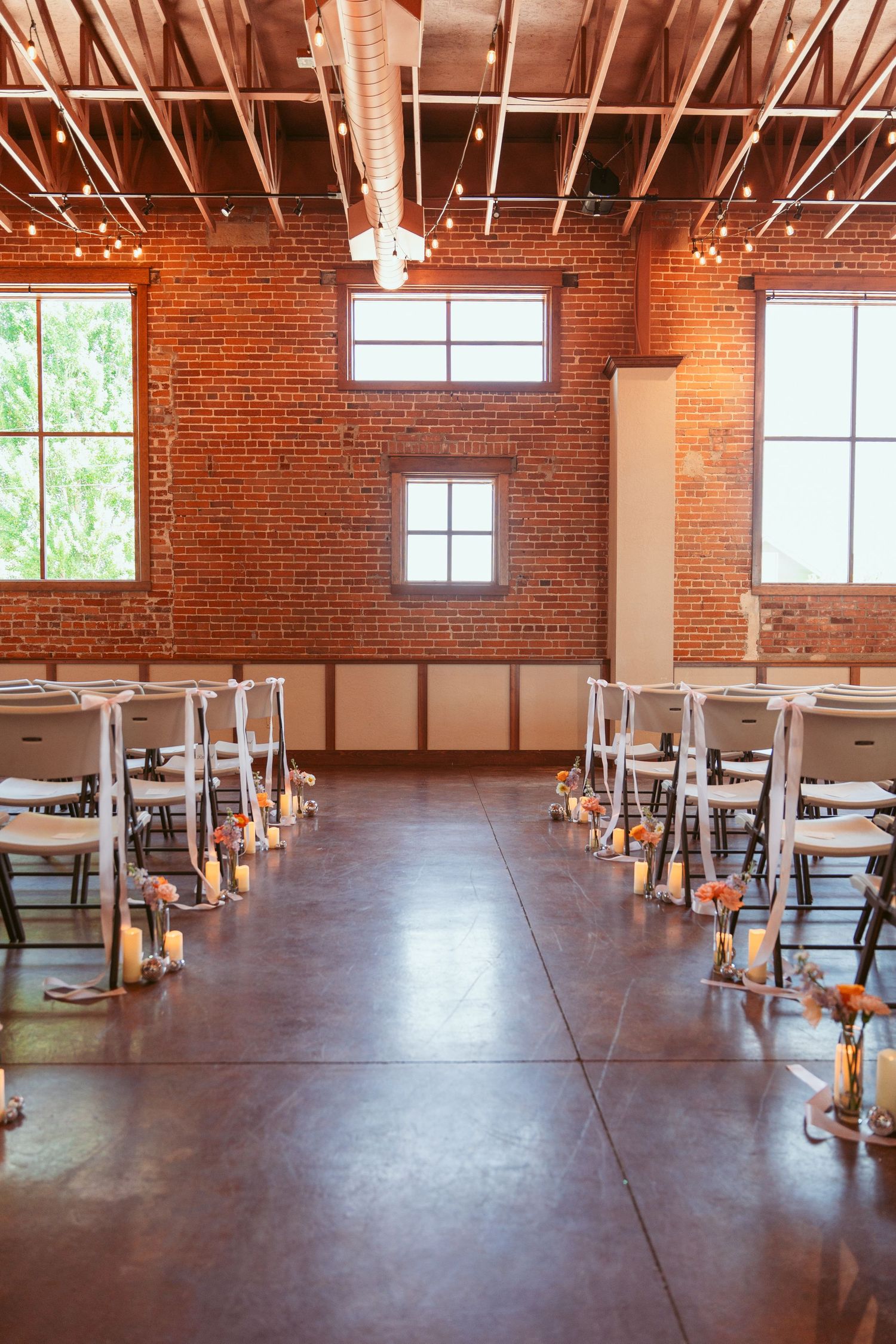 Industrial brick venue space with exposed beams and large windows set up for an event.