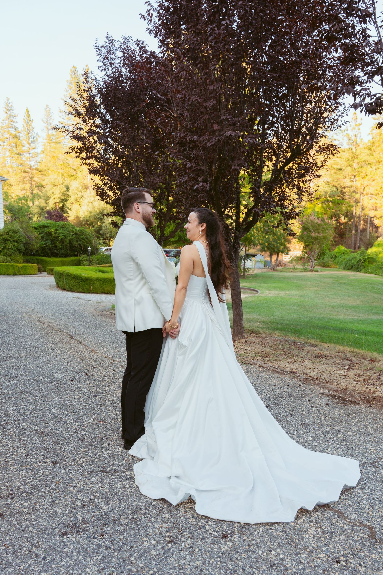 Wedding couple walking and posing on a gravel path during golden hour with flowing white dress.