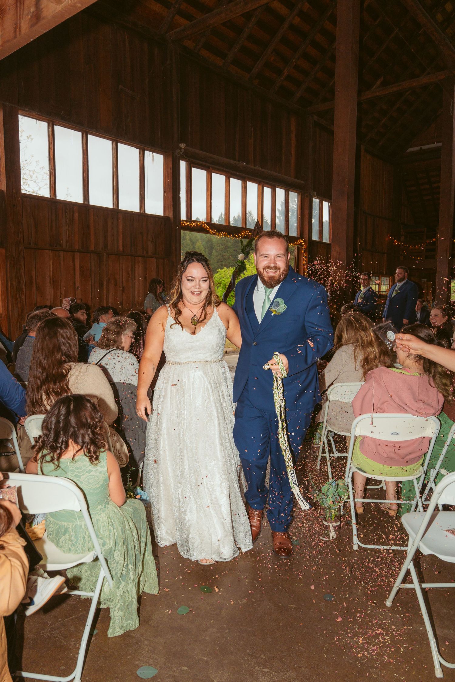 Wedding party celebrating with confetti inside a rustic barn venue.