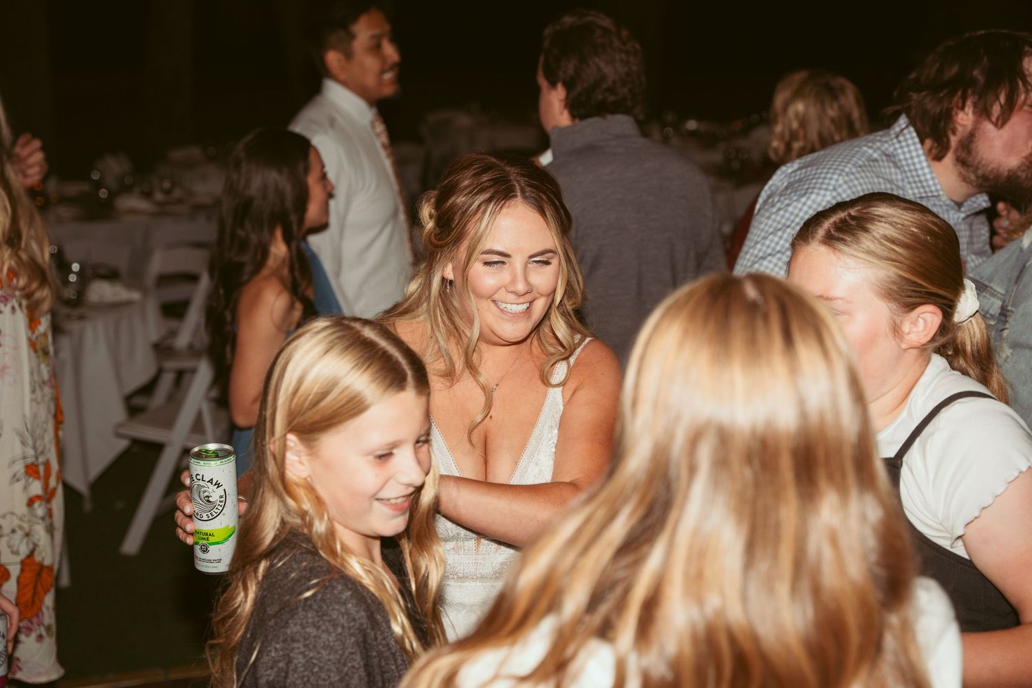 Wedding reception guests mingling and dancing under decorative string lights at night.