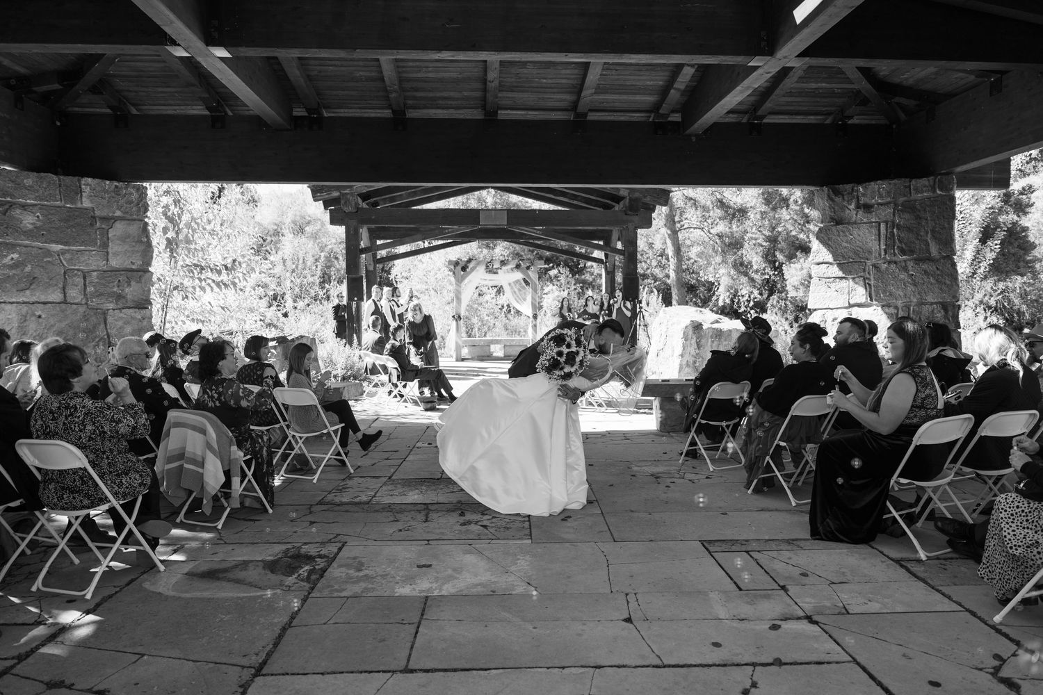 Wide view of a covered outdoor wedding space with folding chairs set up for guests.