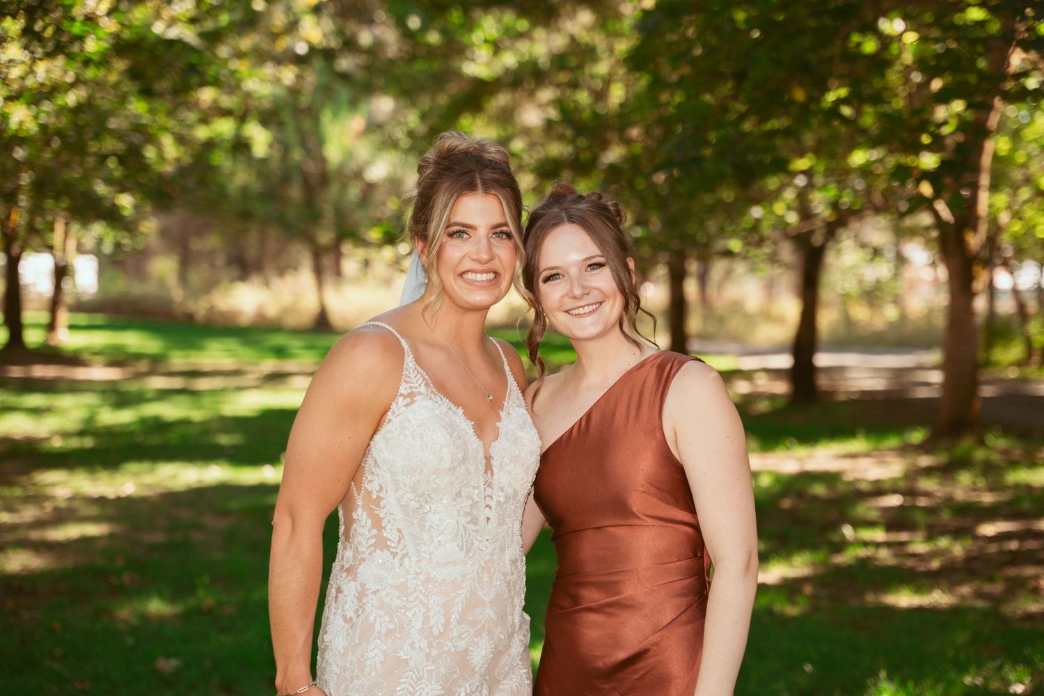 Wedding party members in rust-toned dresses gather for outdoor photos.