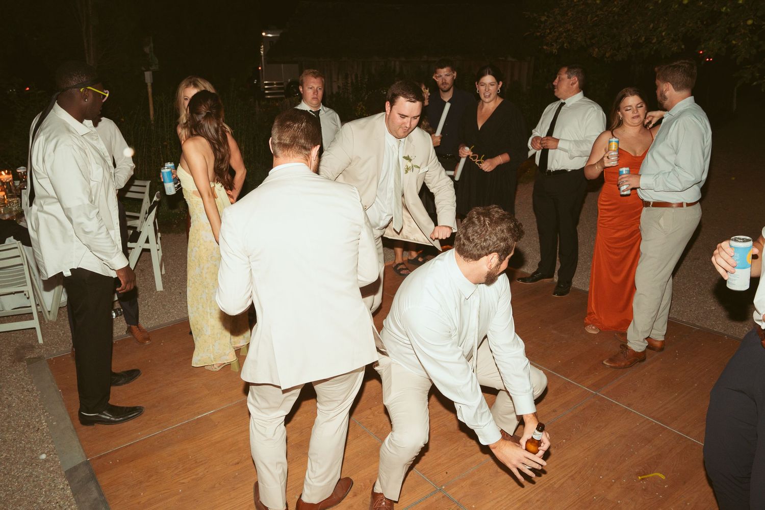 Wedding guests dancing and mingling on an outdoor patio during evening celebrations.