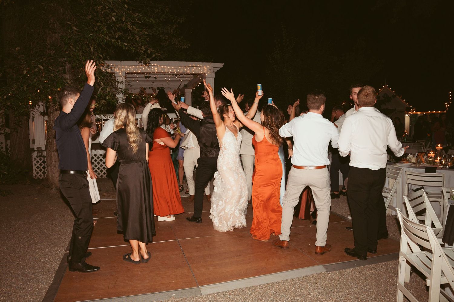 Wedding guests dancing and celebrating on an outdoor dance floor at night.
