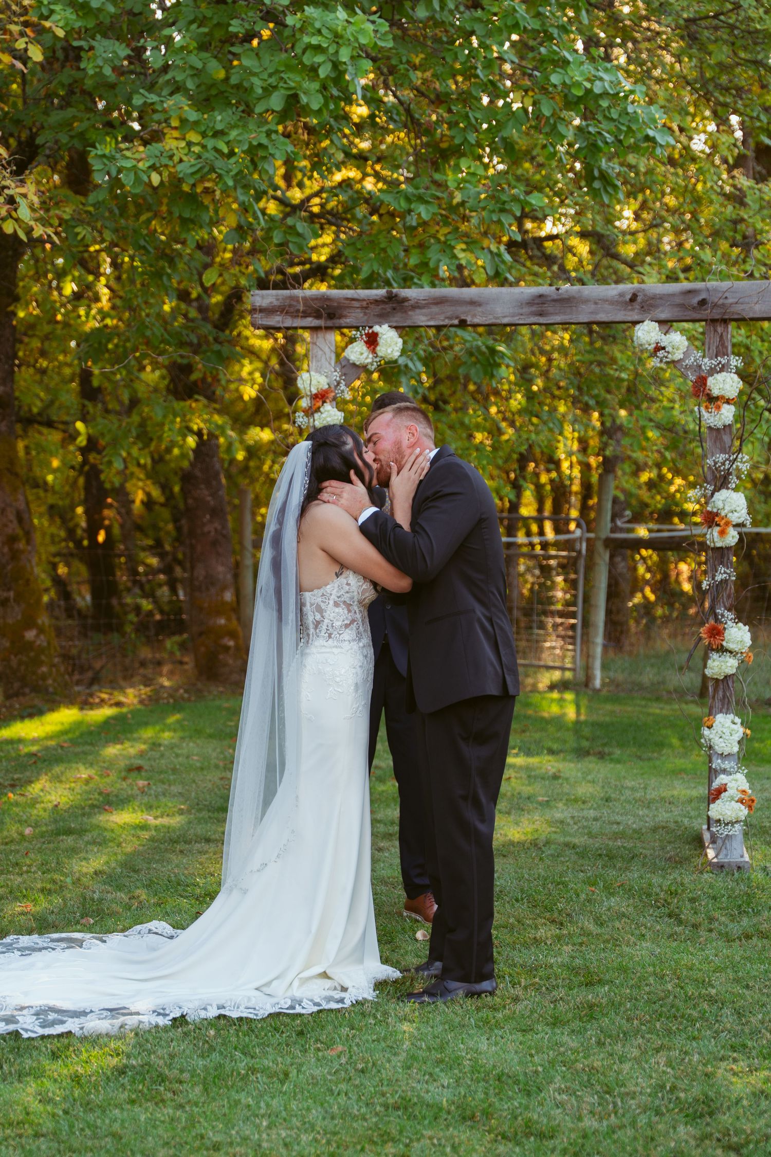 Wedding couple sharing moment under decorated birch trees during autumn outdoor ceremony.