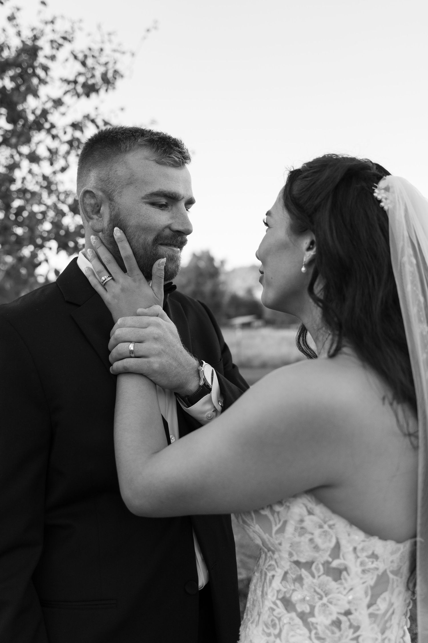 Candid wedding photography captures emotional moments between newlyweds in an outdoor setting.