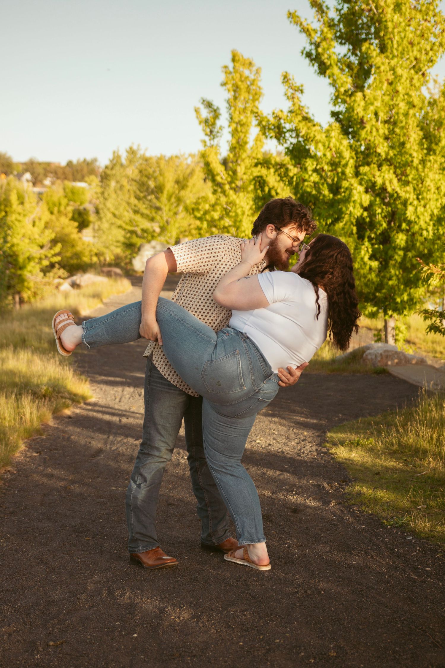 Couple performing romantic dance dip pose outdoors with golden trees in background.