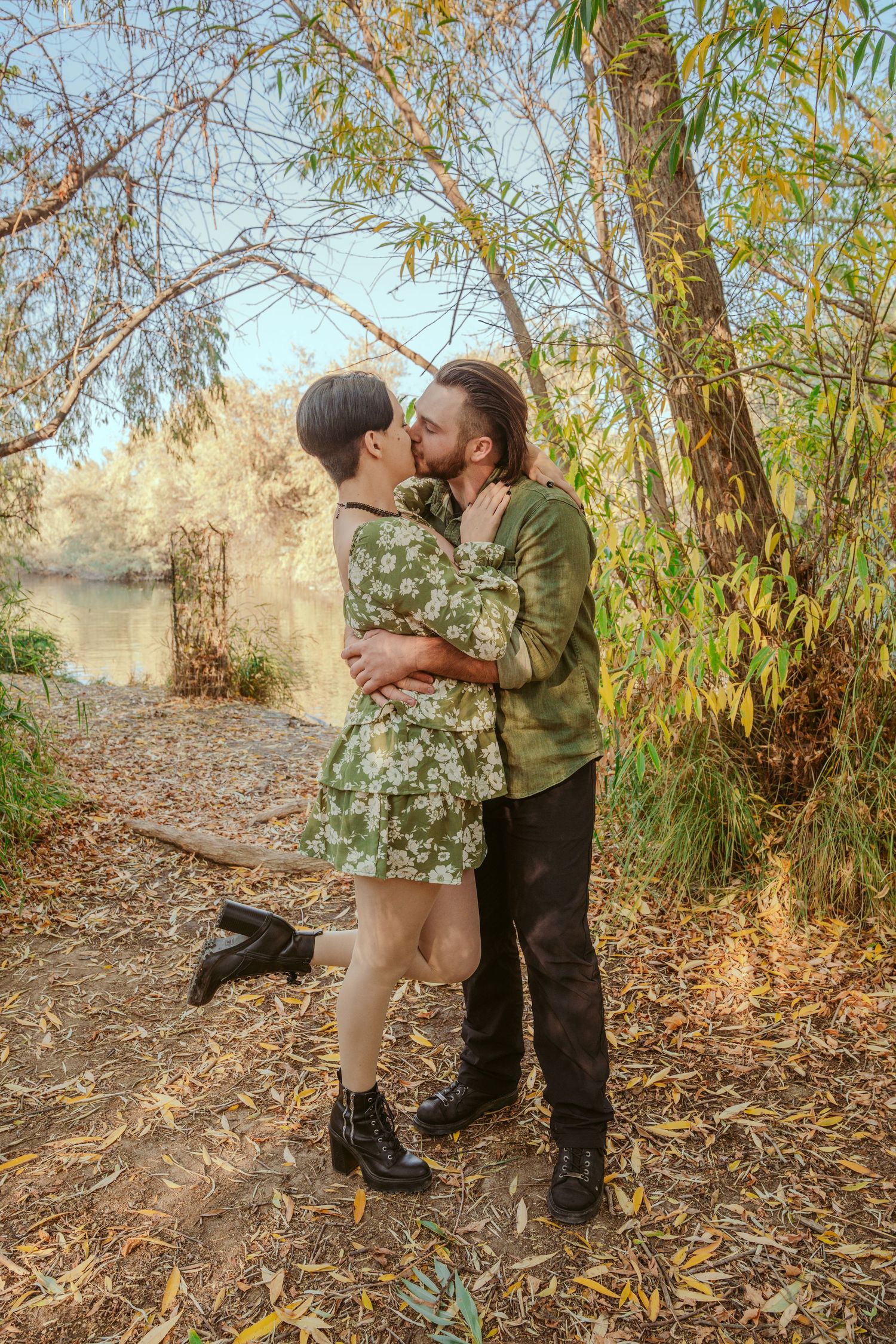 Romantic couple embraces on a wooded trail surrounded by autumn foliage.