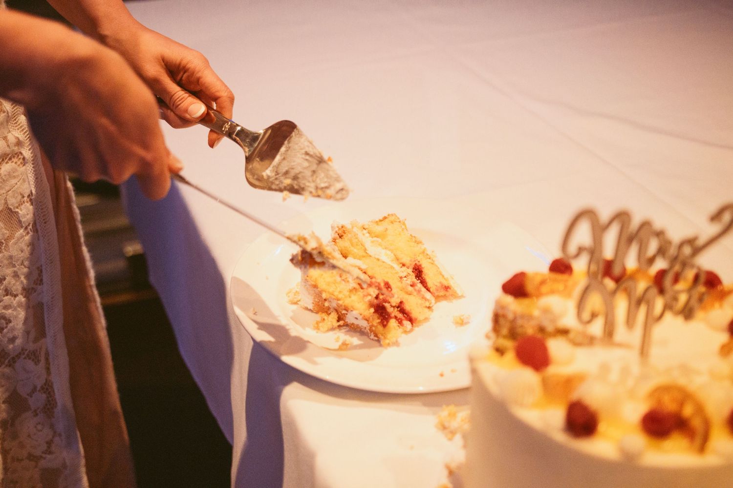 Wedding cake being served on white plates at reception.