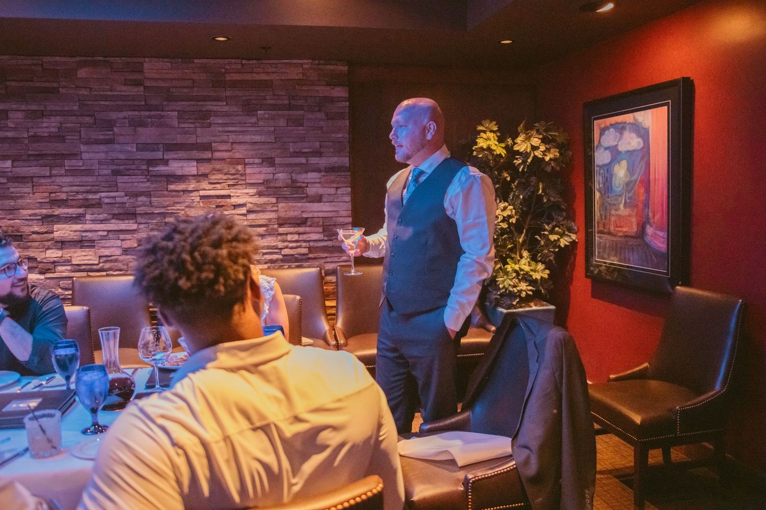 Wedding celebration in intimate restaurant setting with mood lighting and stone wall decor.