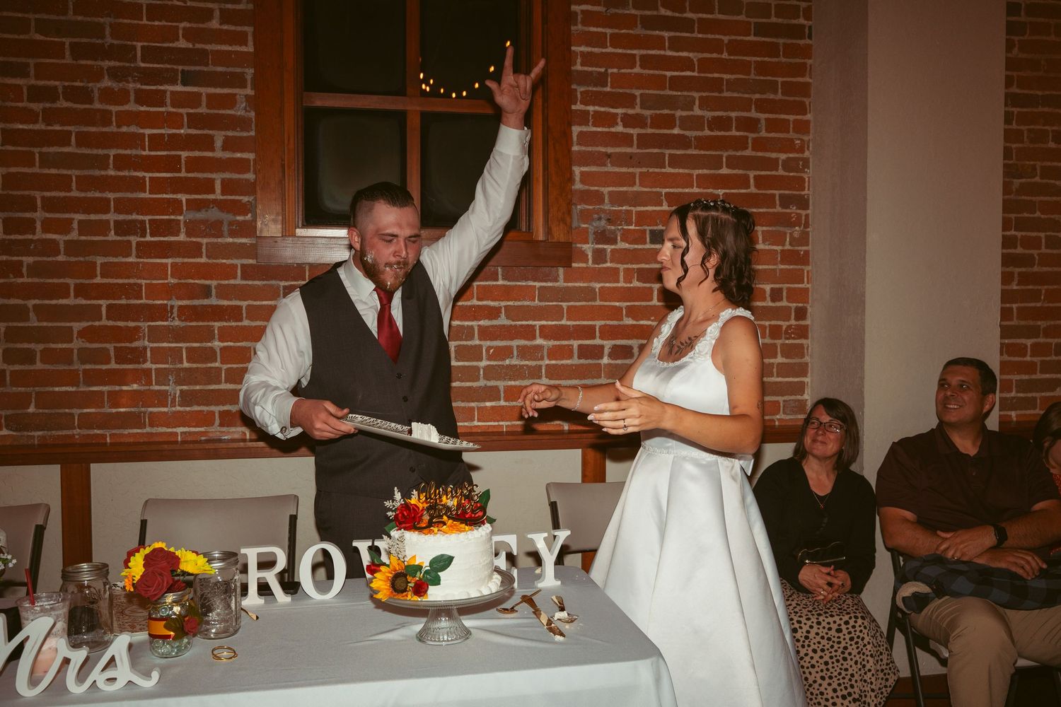 Couple celebrating with raised arms during their wedding cake cutting ceremony.