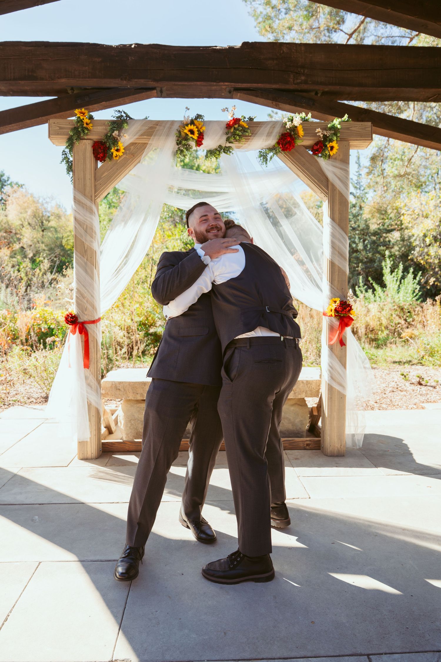 Wedding party members playfully interact under pavilion with fall-themed decorations.
