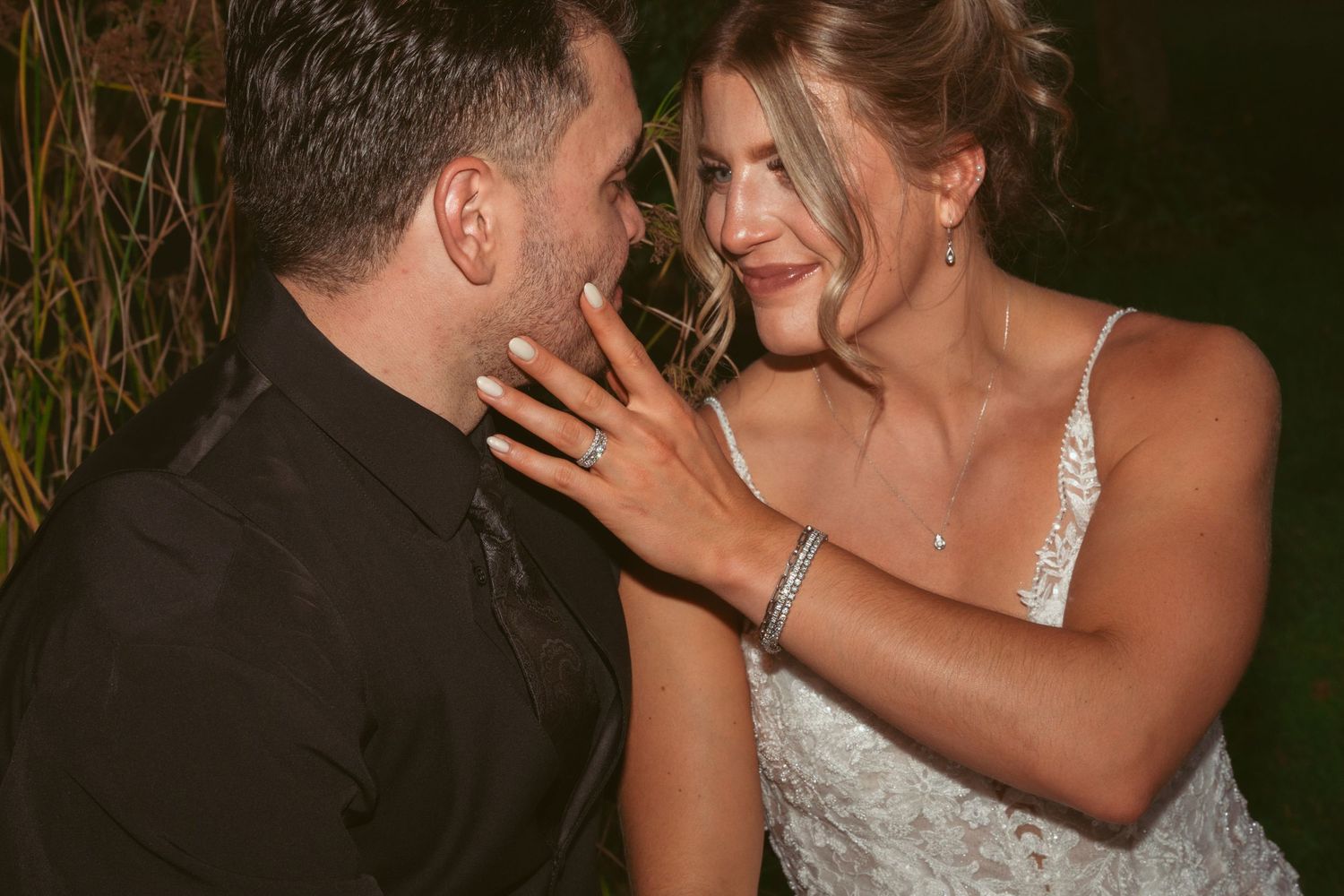 A romantic wedding couple shares an intimate moment during their outdoor evening photoshoot.