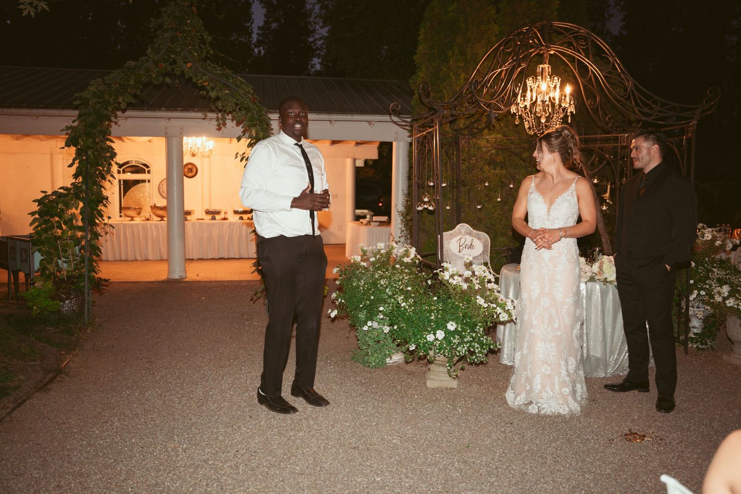 Evening outdoor wedding reception with elegant lighting and floral arrangements.
