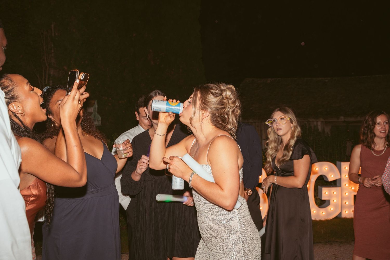 Wedding guests dancing and celebrating on a crowded dance floor at a nighttime reception.