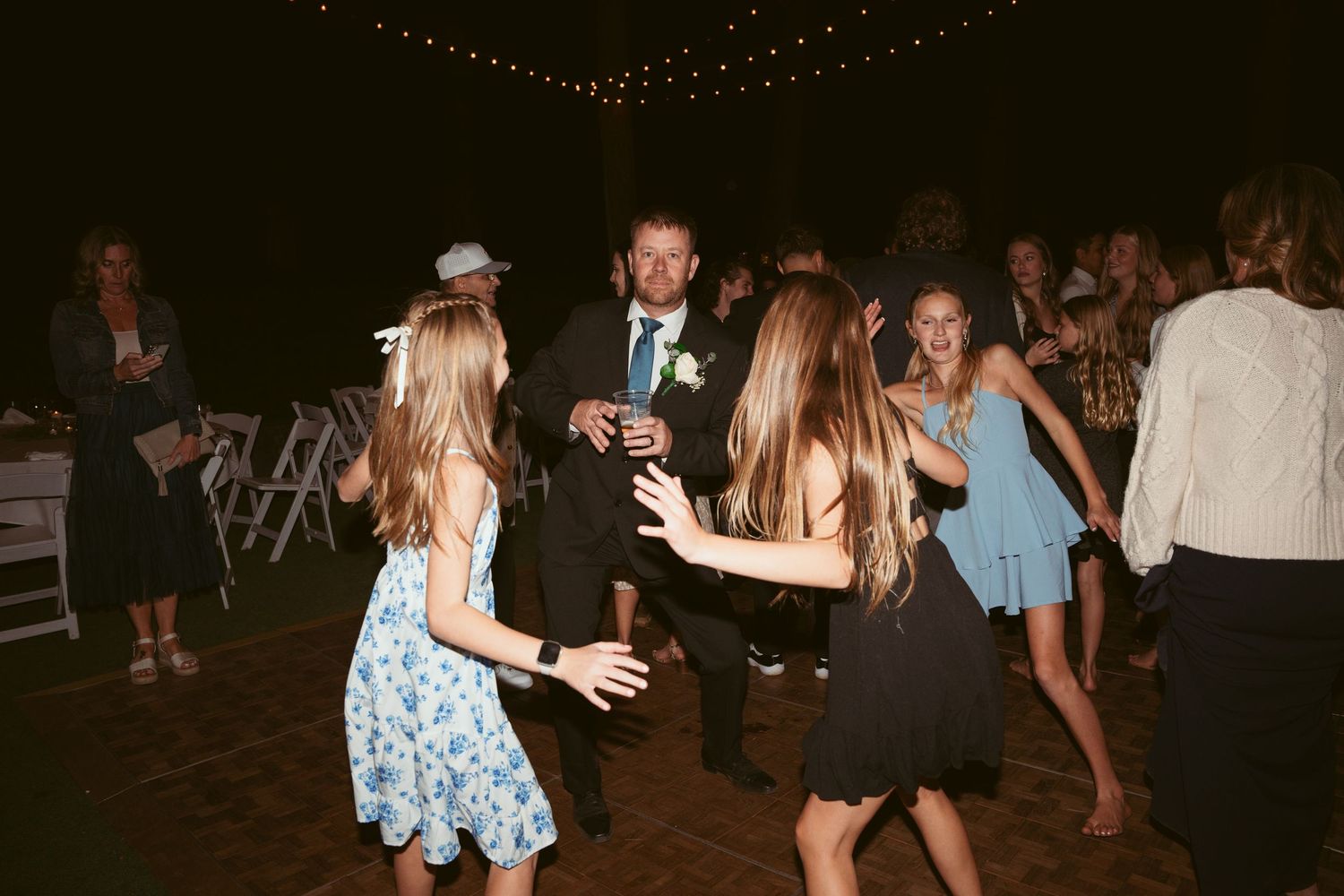 Guests enjoying themselves on a dimly lit outdoor wedding reception dance floor.