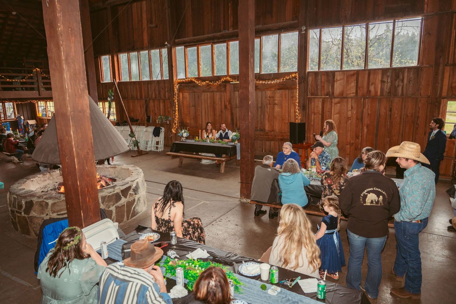 Guests mingling and celebrating at tables inside a wooden barn event space.