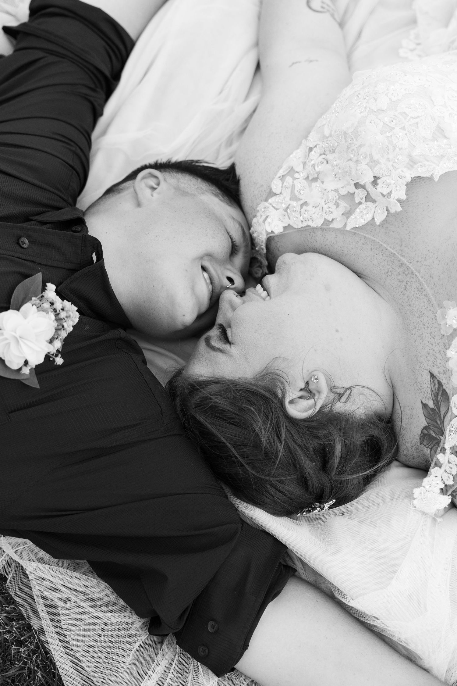 Black and white portrait of newlyweds lying together during outdoor wedding photography session.