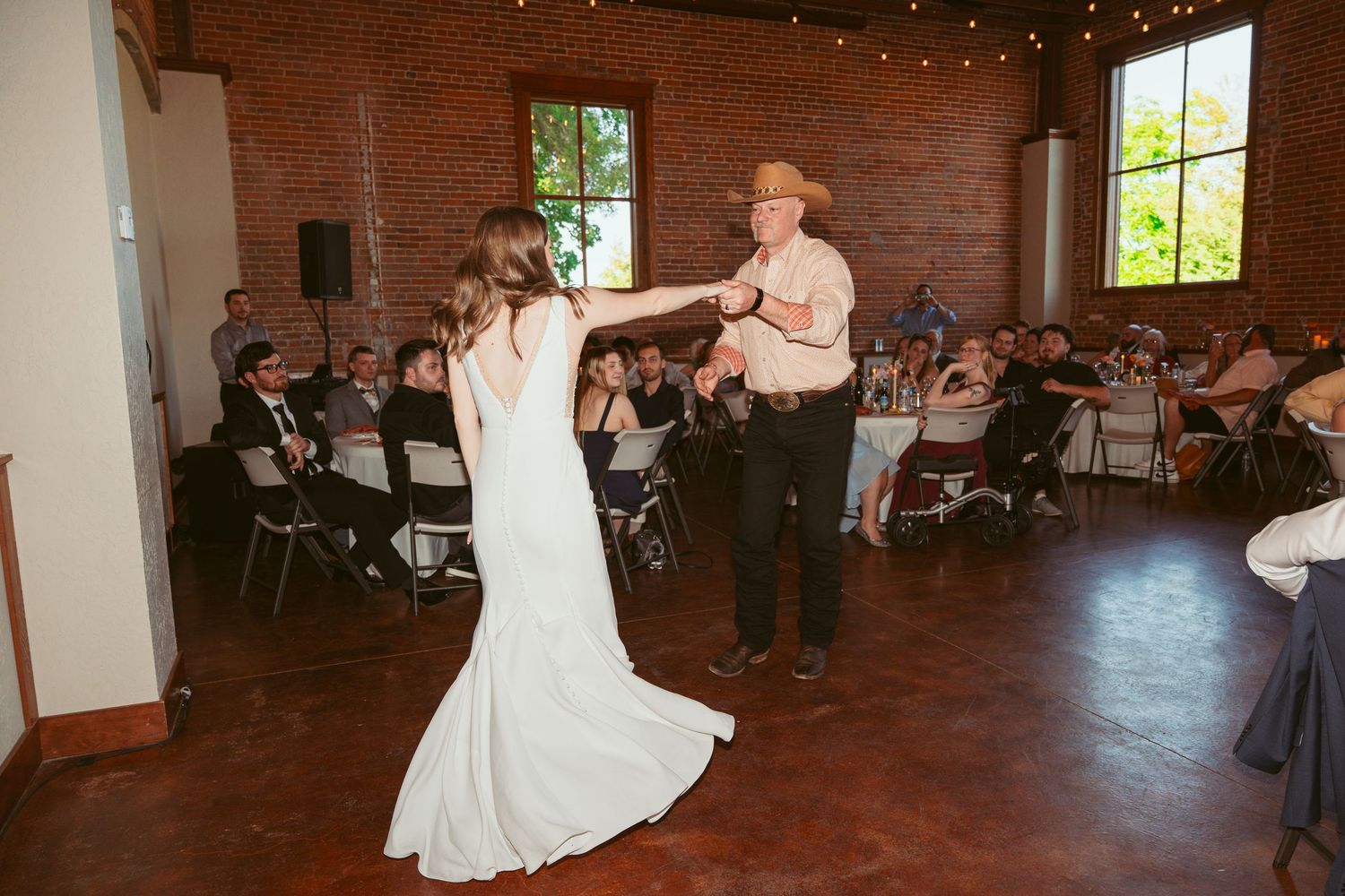 Dancers twirling and spinning on the dance floor at a wedding reception in a historic brick building.