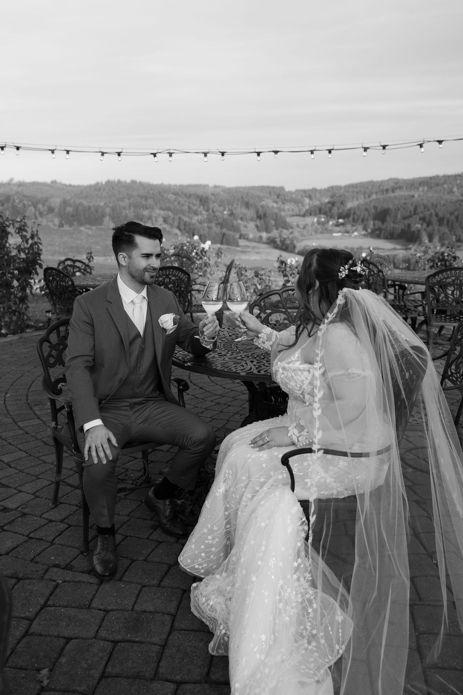 Couple shares candid laughs during wedding photo session on stone patio with mountain views.