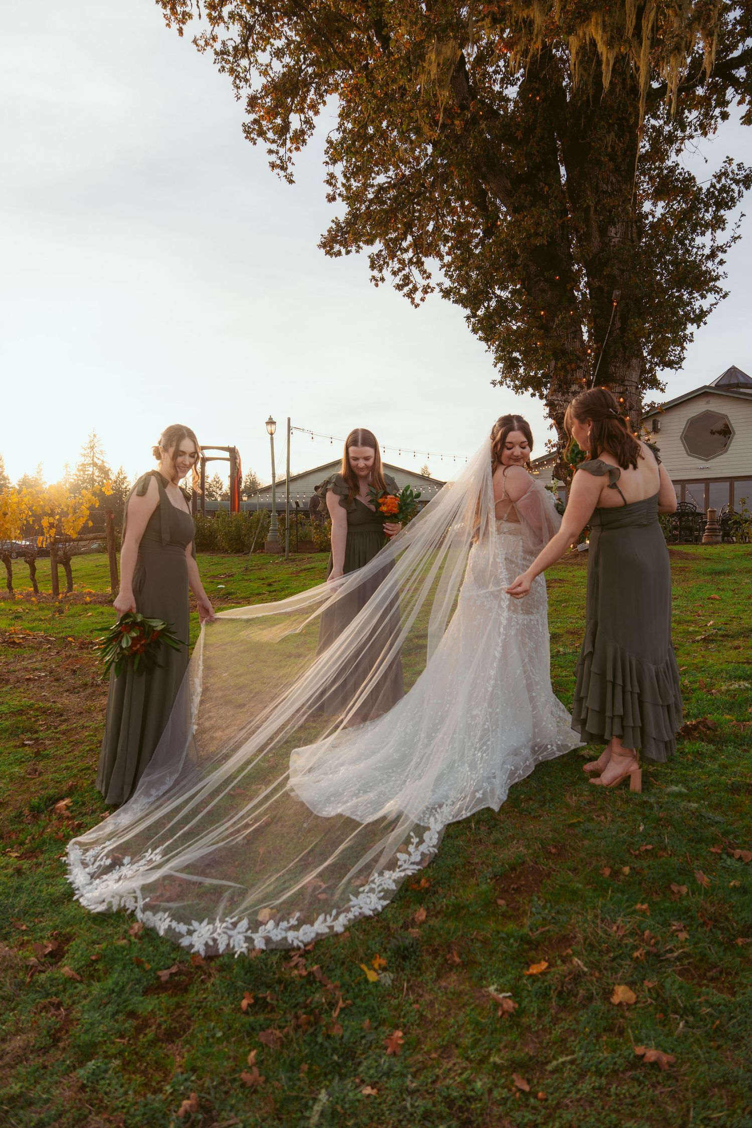 Bridesmaids help arrange bride's cathedral length veil during autumn outdoor photo session.