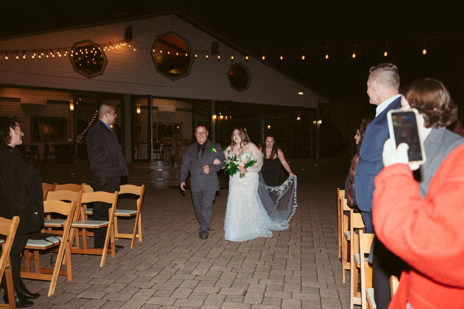 Evening wedding reception with guests mingling on illuminated stone patio.