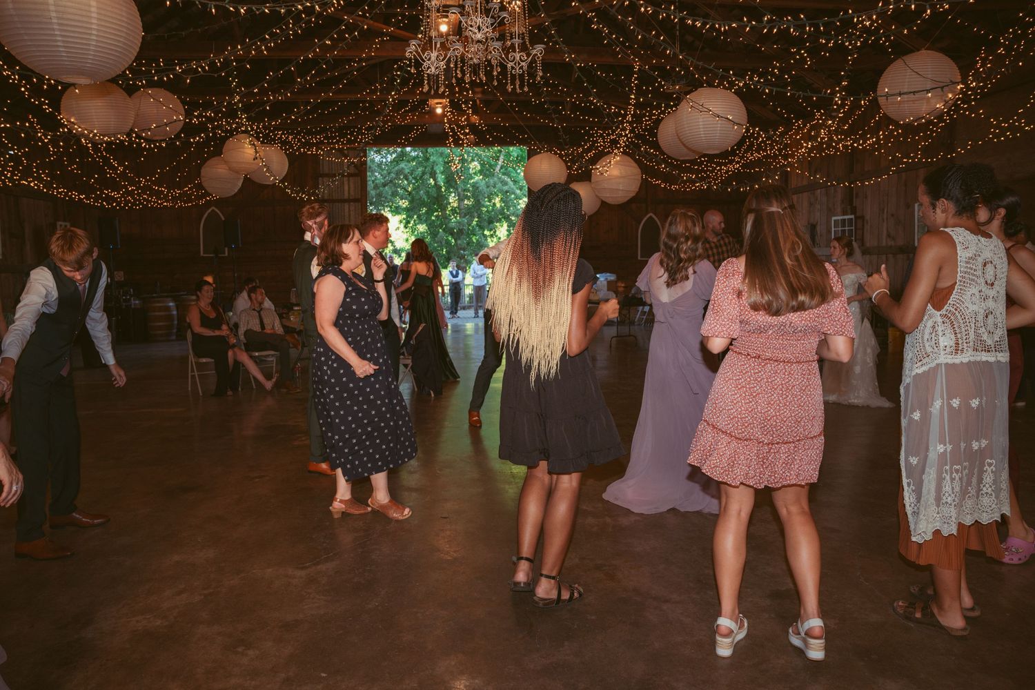 Celebration on dance floor with string lights and lanterns creating warm ambiance.