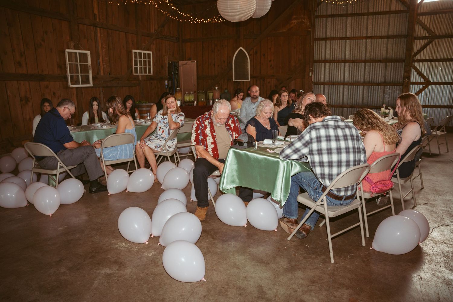 Large barn interior with rows of tables and chairs set for a wedding celebration.