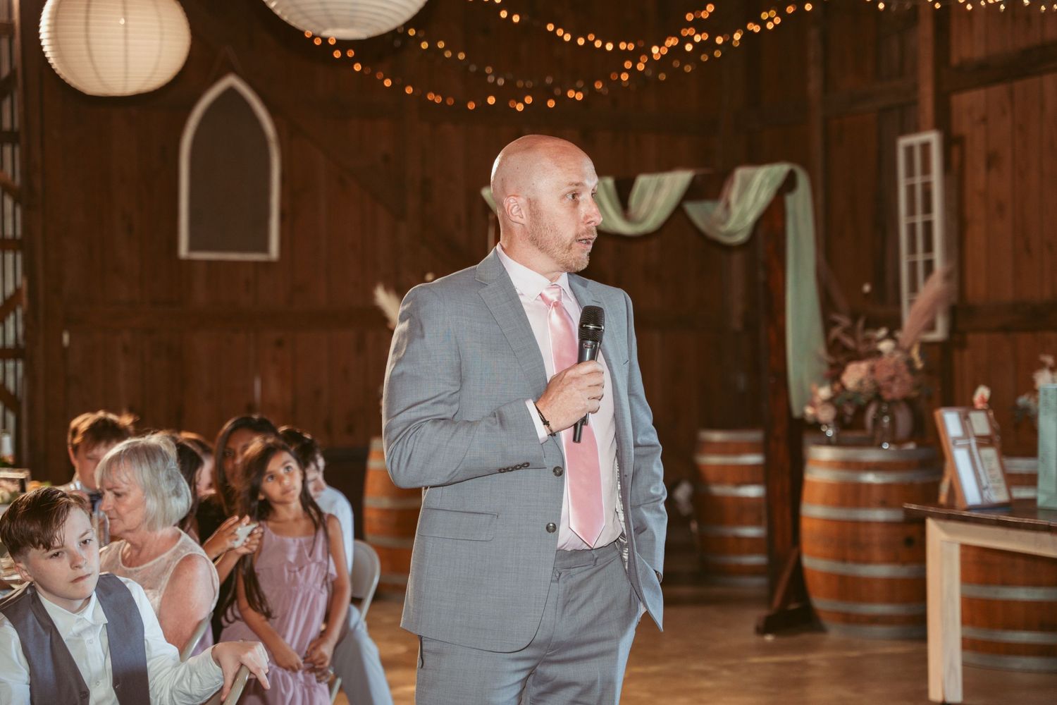 Wedding speeches taking place in a barn venue with romantic lighting and rustic decor.