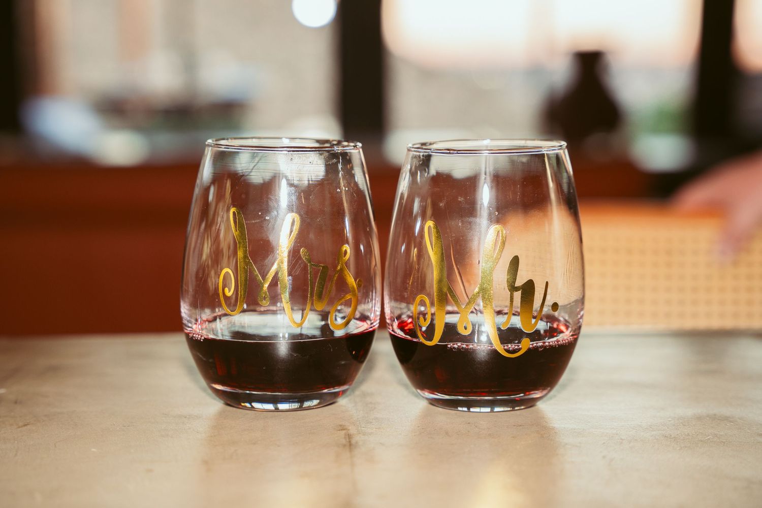 Two wine glasses sit together on a wooden table surface.