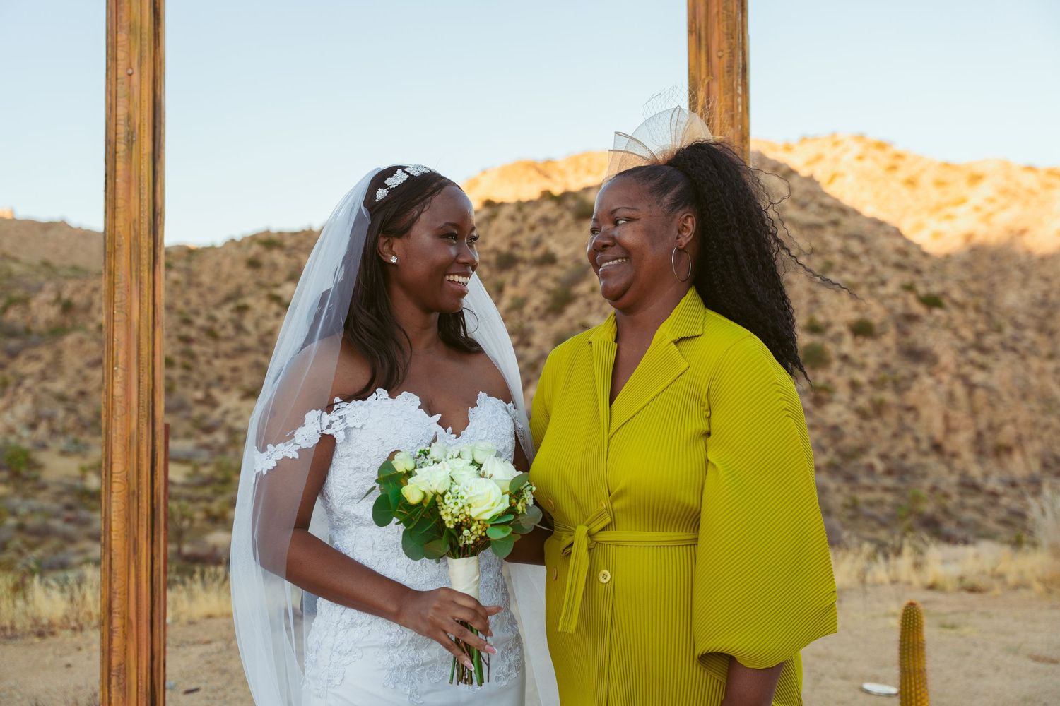 Wedding celebration photos taken under a wooden arch with desert mountains in the golden hour light.