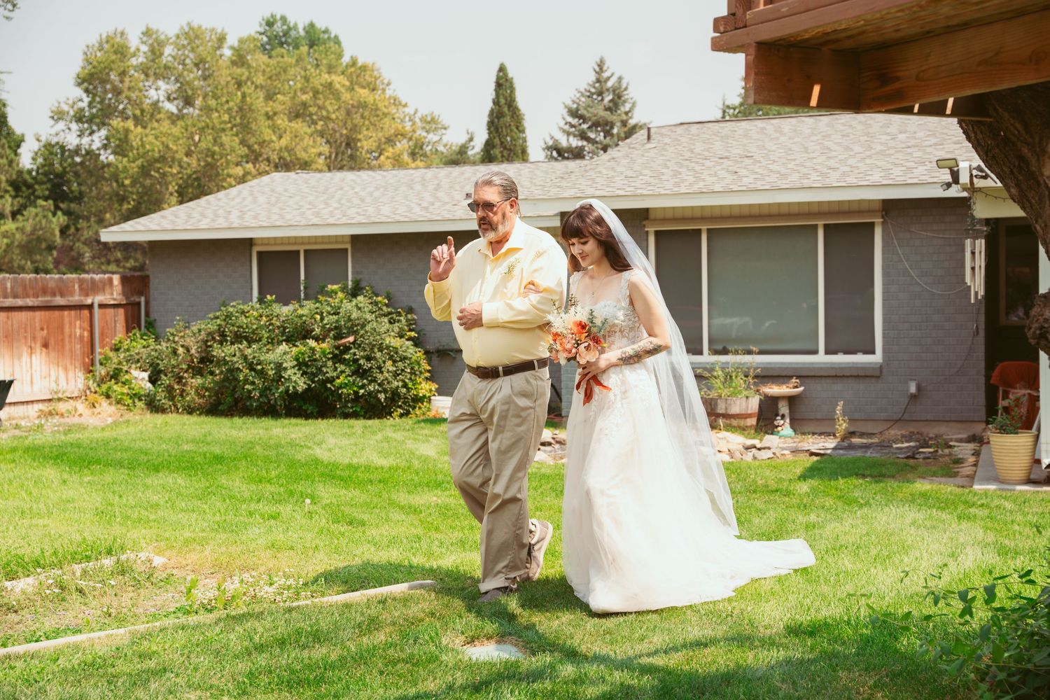 Wedding celebration takes place on a green lawn with residential buildings in the background.