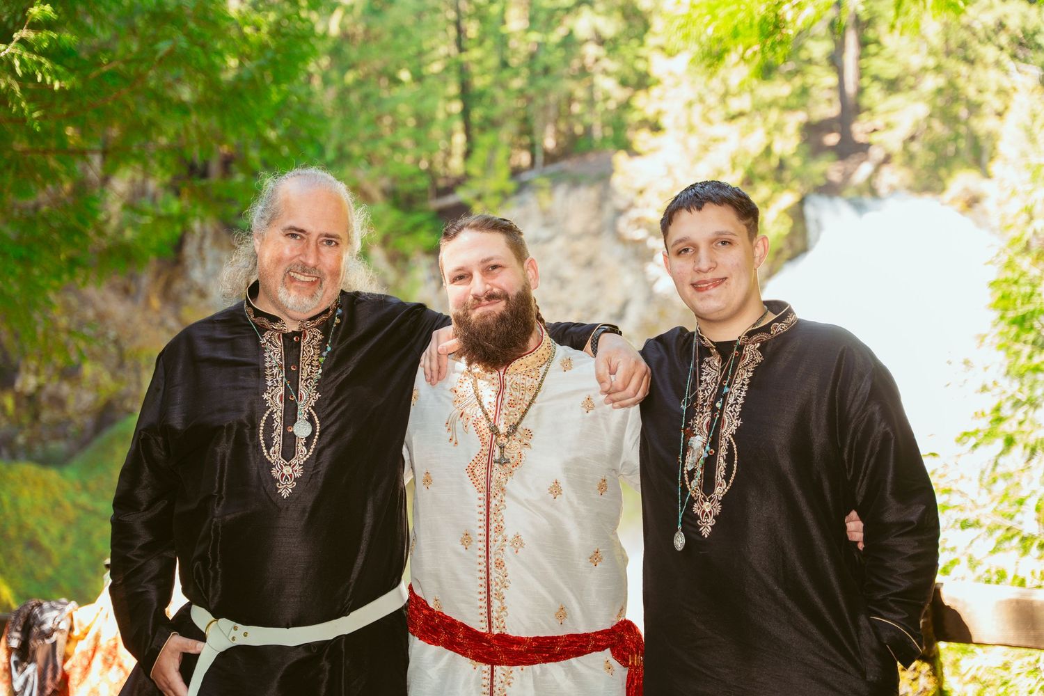 Wedding attendees in traditional medieval costumes gather for group photos in a wooded setting.