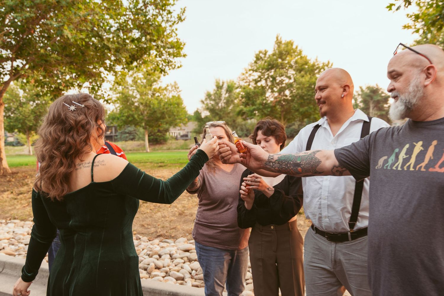 A group of friends sharing a celebratory moment outdoors in a park setting.