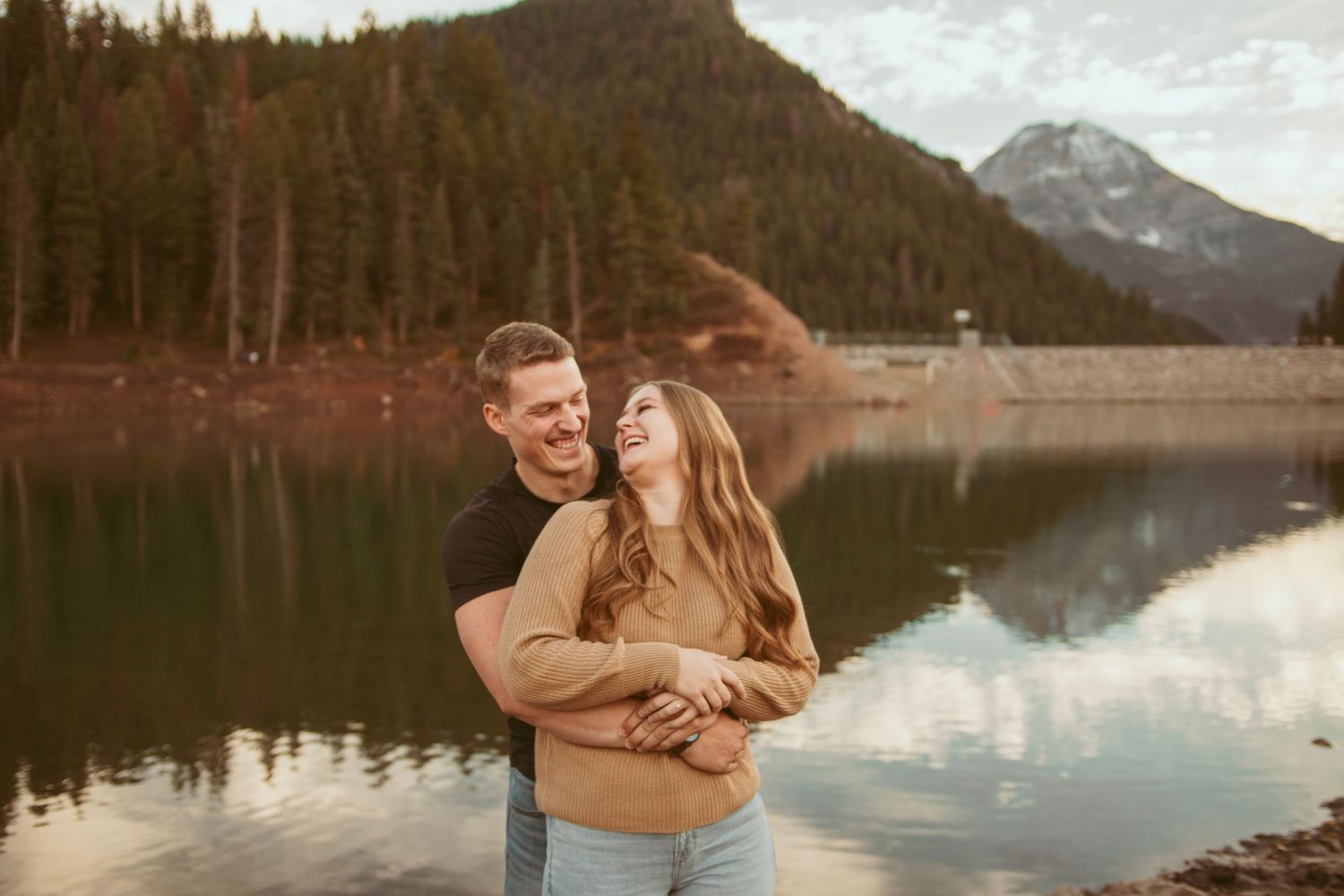 Scenic mountain lake engagement photo session with evergreen trees in the background.