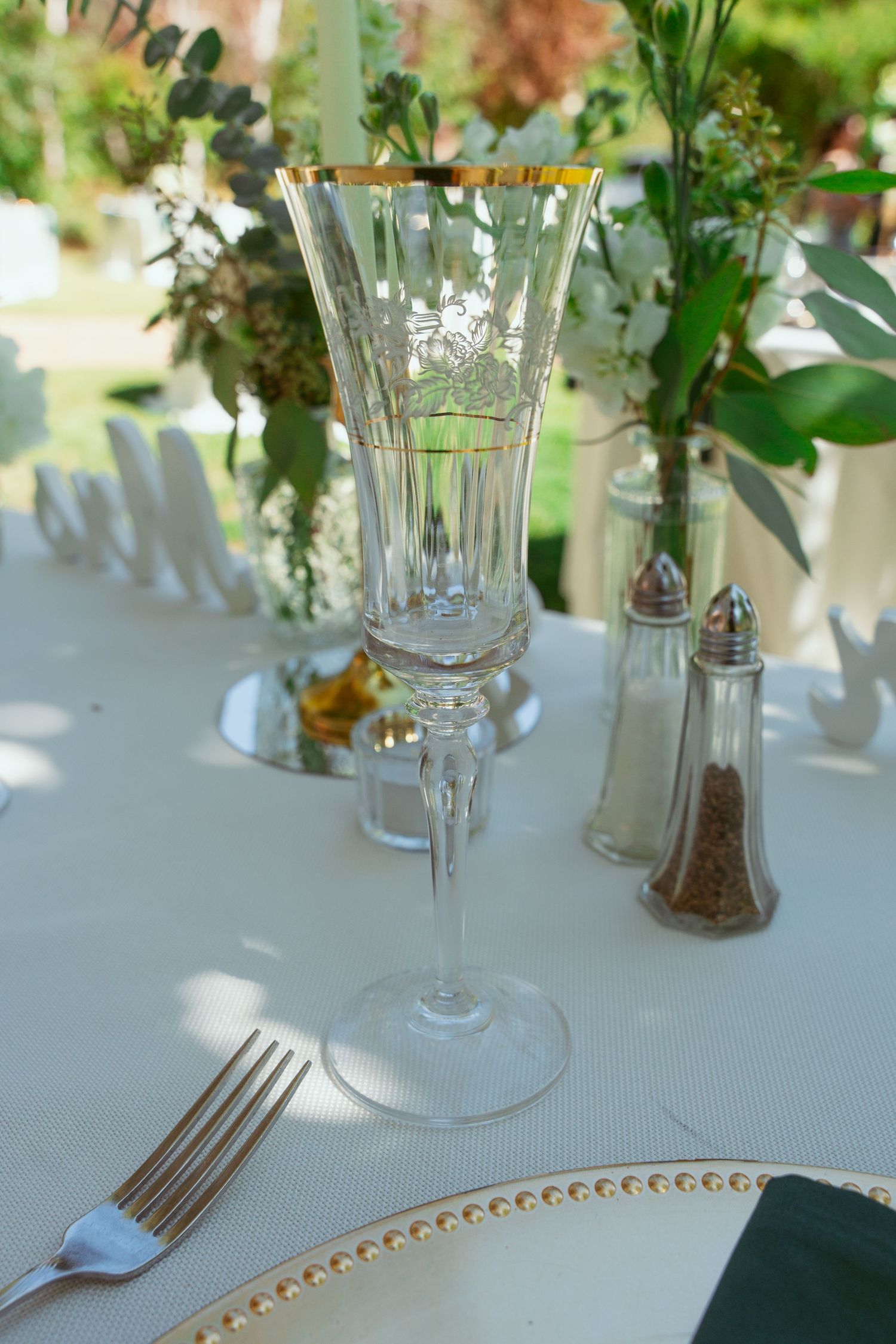Elegant table setting with crystal glasses, white linens, and delicate floral centerpieces.