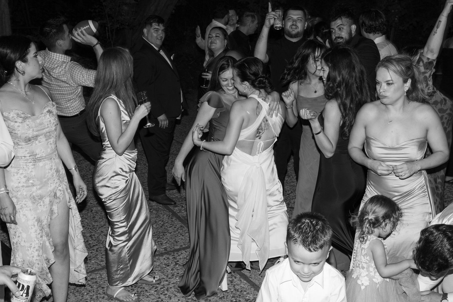 Wedding reception dance floor filled with guests celebrating under twinkling lights at night.