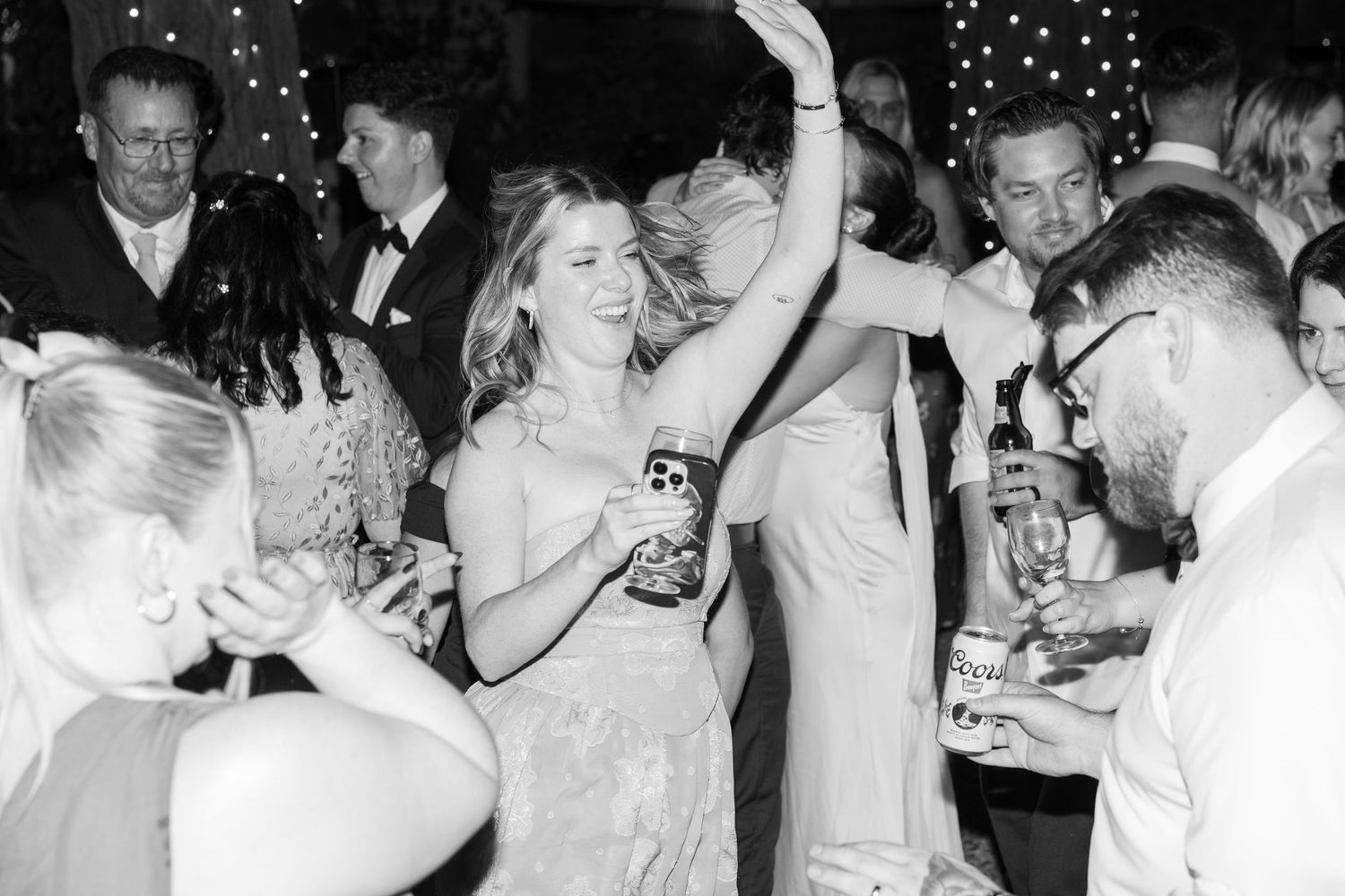 Black and white photo of wedding reception celebration with guests dancing and socializing.